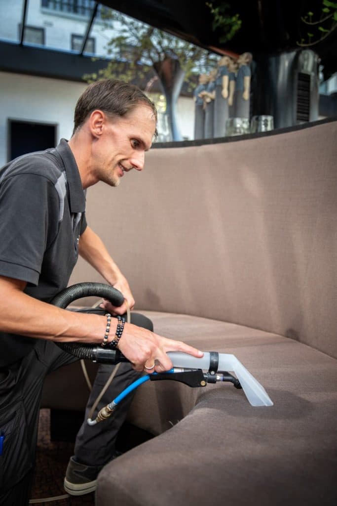Specialist reinigt bank met professionele extractie-apparatuur