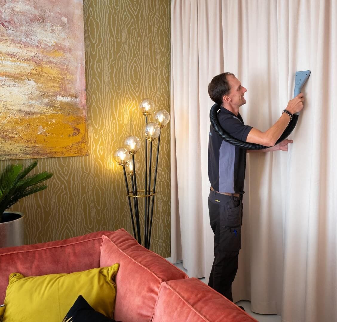 Specialist reinigt gordijnen aan de rail met sproei-extractie