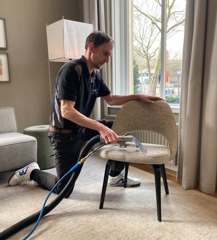 Specialist reinigt een gestoffeerde stoel thuis met sproei-extractie