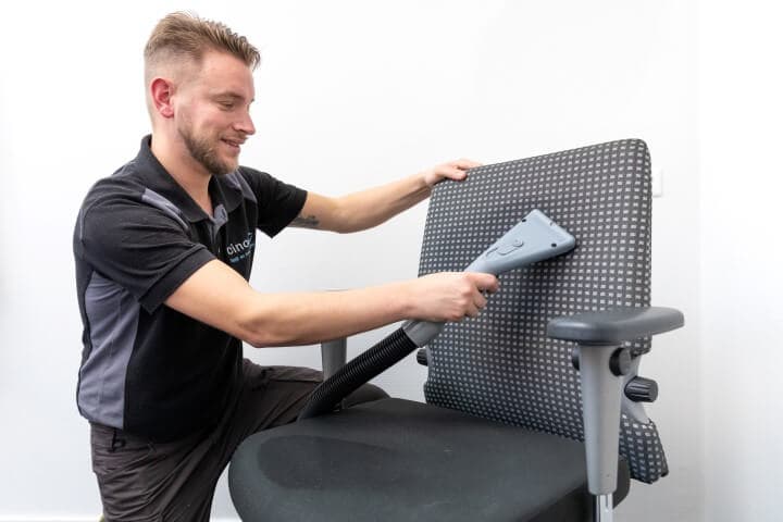 Specialist reinigt bureaustoel met professionele apparatuur