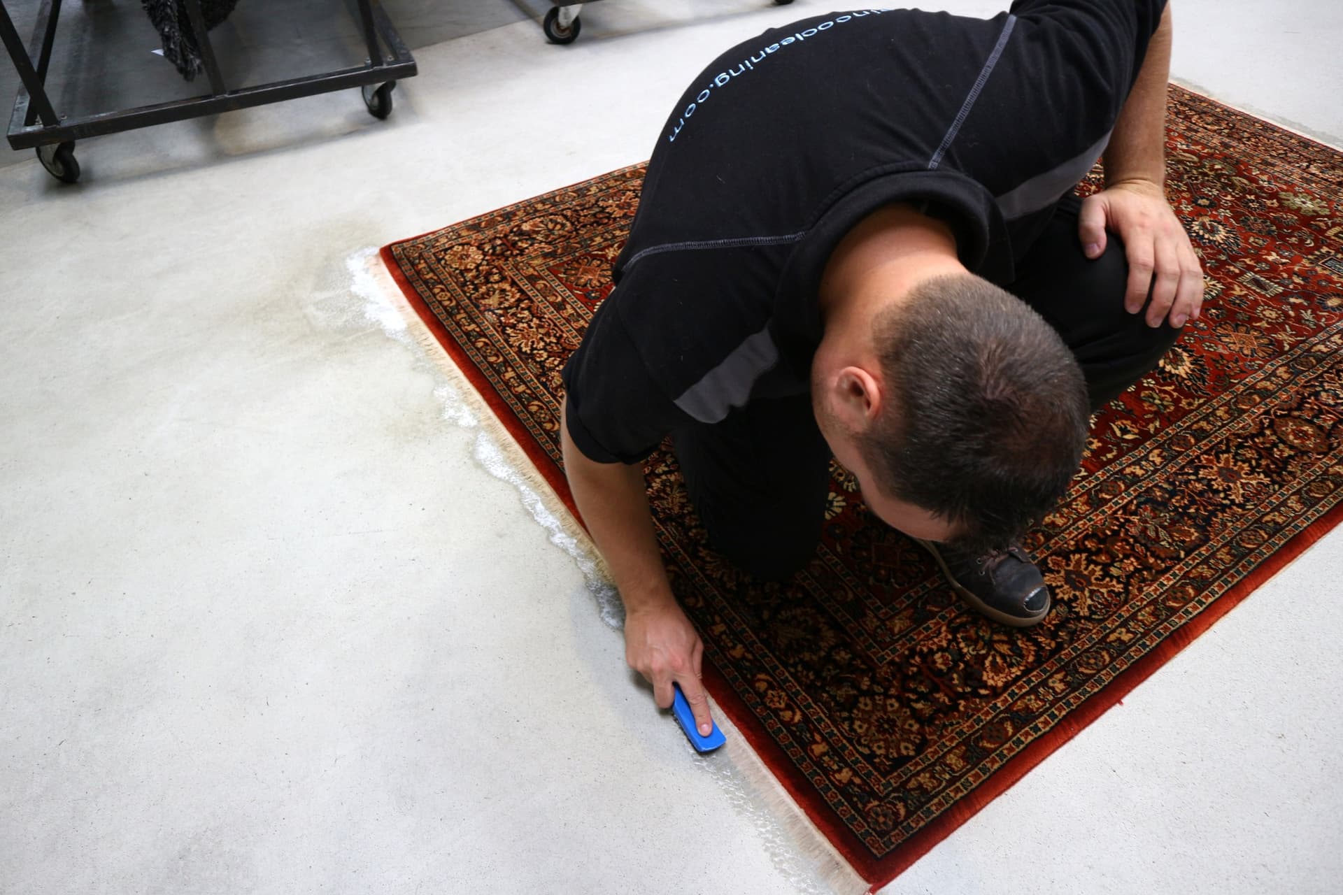 Specialist reinigt de franje van een antiek Perzisch vloerkleed met een handborstel