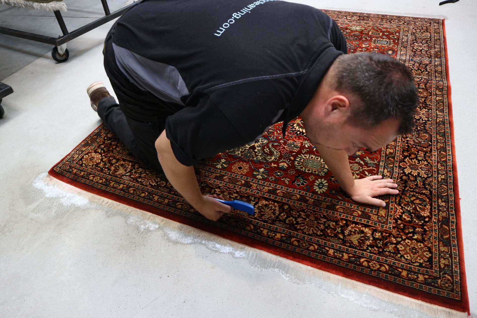 Specialist behandelt een rood Perzisch vloerkleed met een handborstel