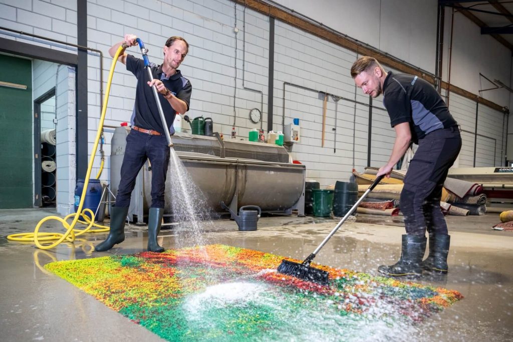 2 specialisten sproeien en reinigen het vloerkleed