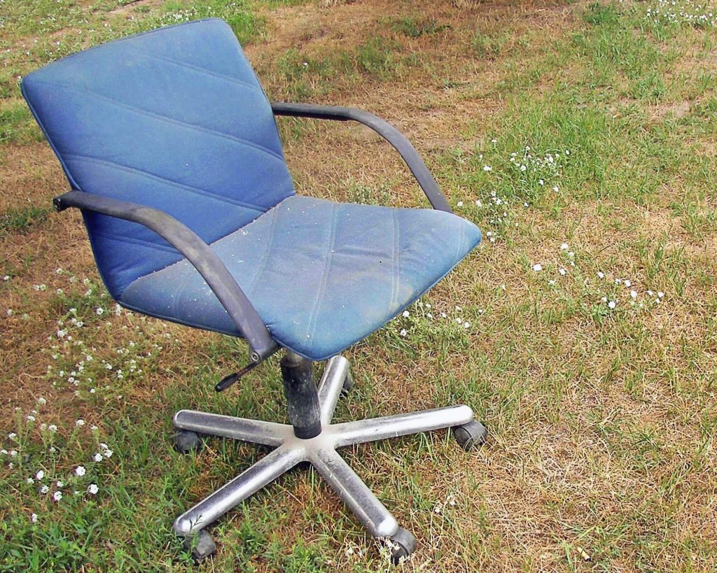 Vieze blauwe bureaustoel in het gras